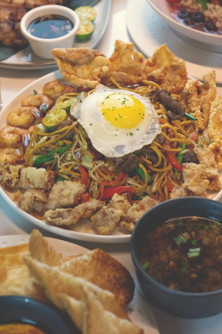 Pancit Batil Patong at Halina: stir-fried egg noodles with crispy pork, chicken skin and a fried egg, with broth on the side